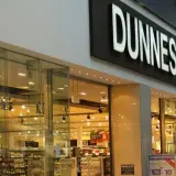 Wejście do sklepu Dunnes Stores, irlandzkiej sieci handlowej. Widać jasne oświetlenie i półki z produktami.