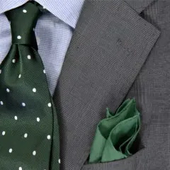 Szara marynarka w kratę, błękitna koszula, zielony krawat w kropki i zielona poszetka.
