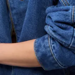 Rękaw kurtki z niebieskiego denimu, zapięcie na zamek błyskawiczny i guzik. To jest właśnie denim!