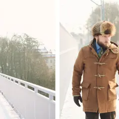 Mężczyzna w futrzanej czapce i płaszczu samarka idzie po zaśnieżonym moście.