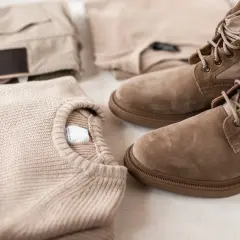 Sweter i spodnie w kolorze karmelowym, obok nich buty trekkingowe.