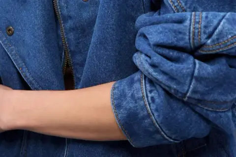 Rękaw kurtki z niebieskiego denimu, zapięcie na zamek błyskawiczny i guzik. To jest właśnie denim!