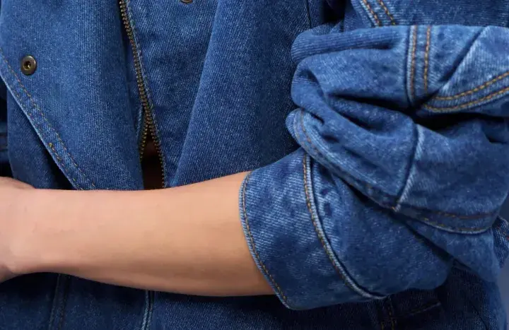 Rękaw kurtki z niebieskiego denimu, zapięcie na zamek błyskawiczny i guzik. To jest właśnie denim!