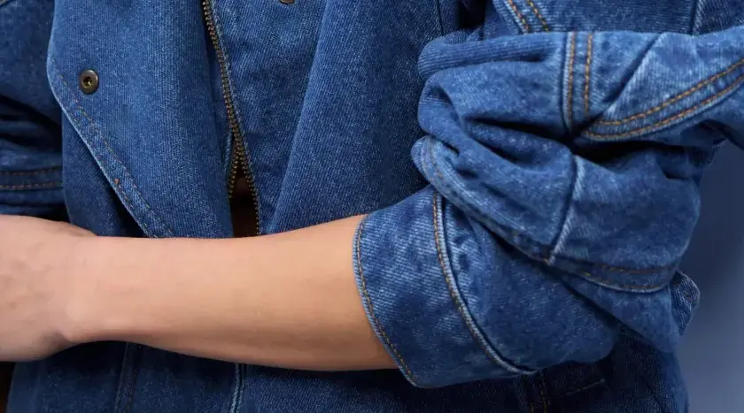 Rękaw kurtki z niebieskiego denimu, zapięcie na zamek błyskawiczny i guzik. To jest właśnie denim!